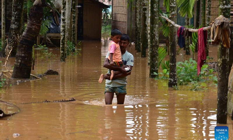 A villager carries a child as he wades through flood water after heavy rains following the landfall of Cyclone Remal in Nagaon district, Assam, northeastern India, on May 29, 2024. Storms and rainfall-induced landslides triggered in the aftermath of Cyclone Remal killed at least 32 people and injured many others across India's West Bengal and four northeastern states, officials said Tuesday.(Photo: Xinhua)