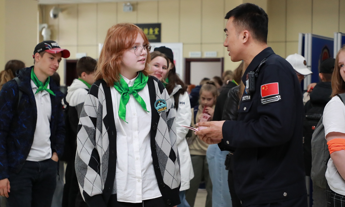 A Border inspection officer from Heihe talks to a Russian child at Heihe Port, Northeast China's Heilongjiang Province, on May 28, 2024. That morning, 280 Russian children arrived by ferry at Heihe Port to start a Children's Day exchange visit between Chinese and Russian children.