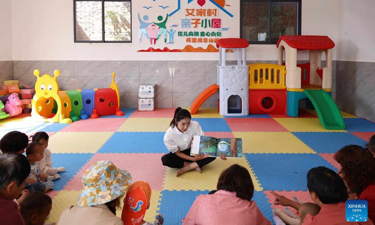 A volunteer reads a book for children at a Community Based Family Support (CBFS) center in Aijia Village, Yichang City of central China's Hubei Province, April 23, 2024. (Photo: Xinhua)