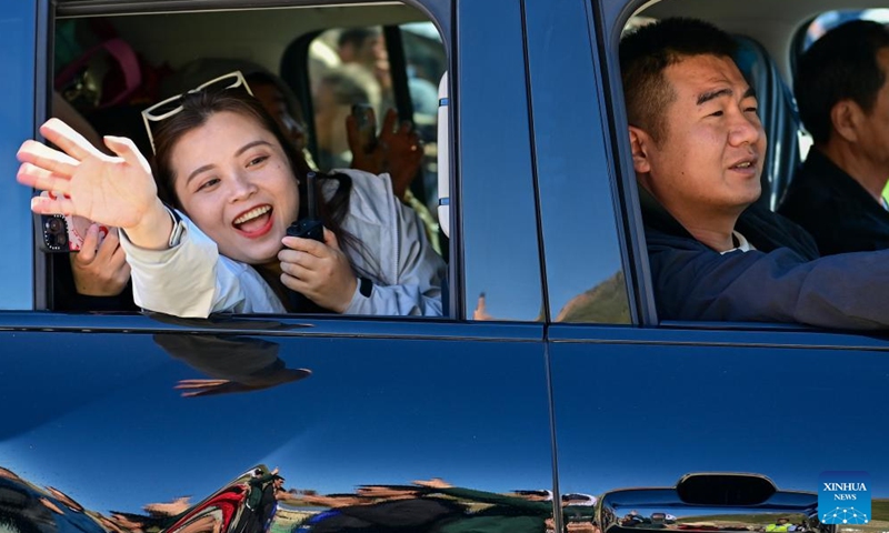 A tourist waves to local people at a service station along the Duku Highway in Usu City, northwest China's Xinjiang Uygur Autonomous Region, June 1, 2024. (Photo: Xinhua)