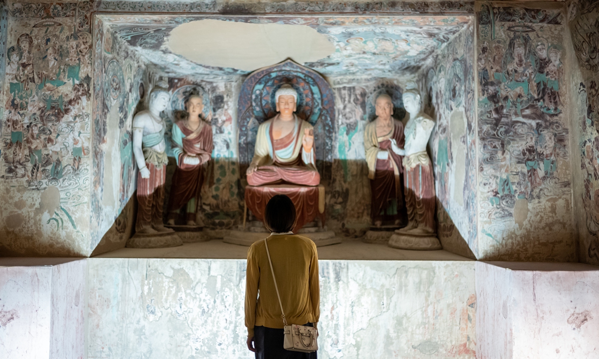A visitor explores an exhibition on the Mogao Caves held in Beijing. Photo: IC
