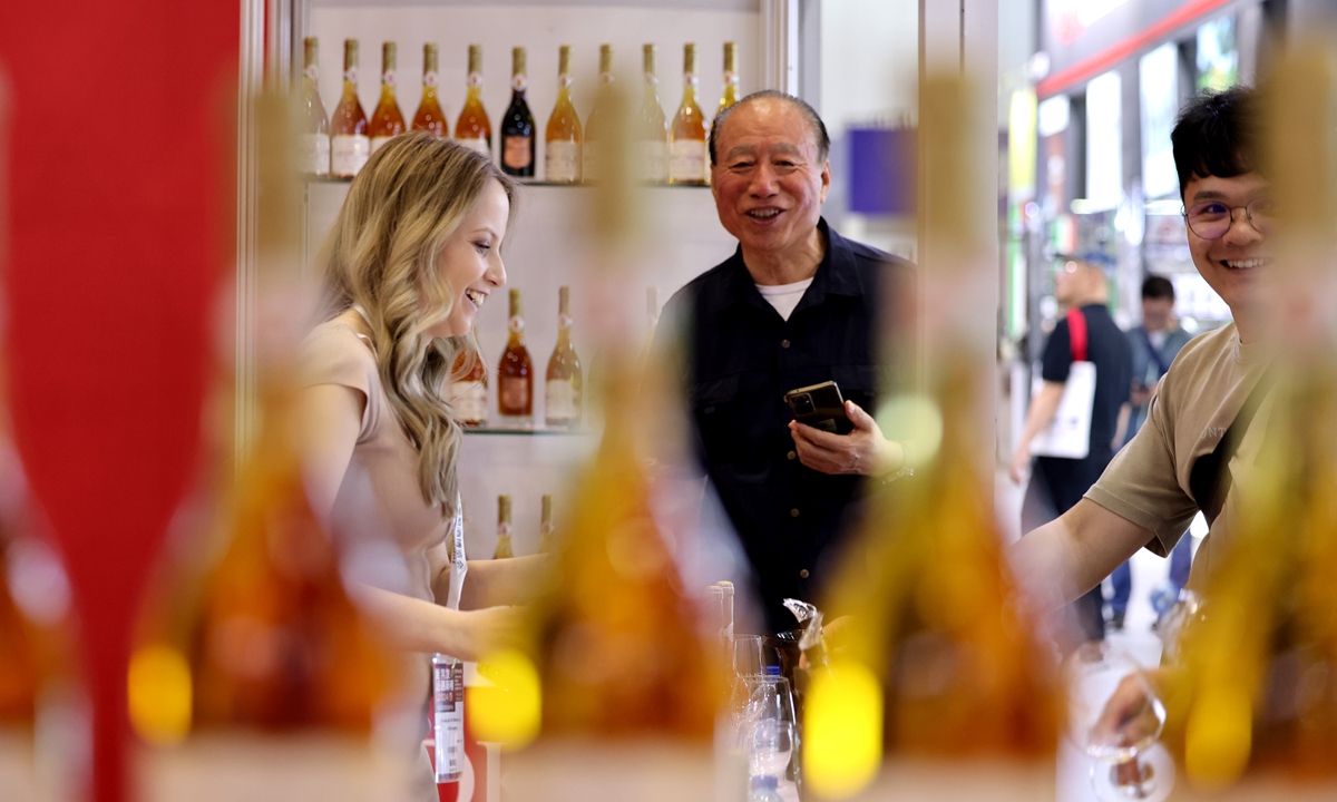 A salesperson (left) introduces wine to Chinese customers at an international wine expo in Beijing on June 4, 2024. China's wine industry achieved sales of 9.09 billion yuan ($1.26 billion) in 2023, up 4.8 percent year-on-year, according to industry sources. Photo: cnsphoto