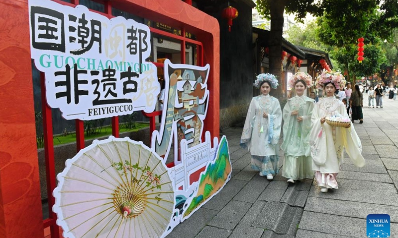 Tourists with floral head decorations walk in the ancient Sanfangqixiang (Three Lanes and Seven Alleys) area in Fuzhou, southeast China's Fujian Province, June 7, 2024. 