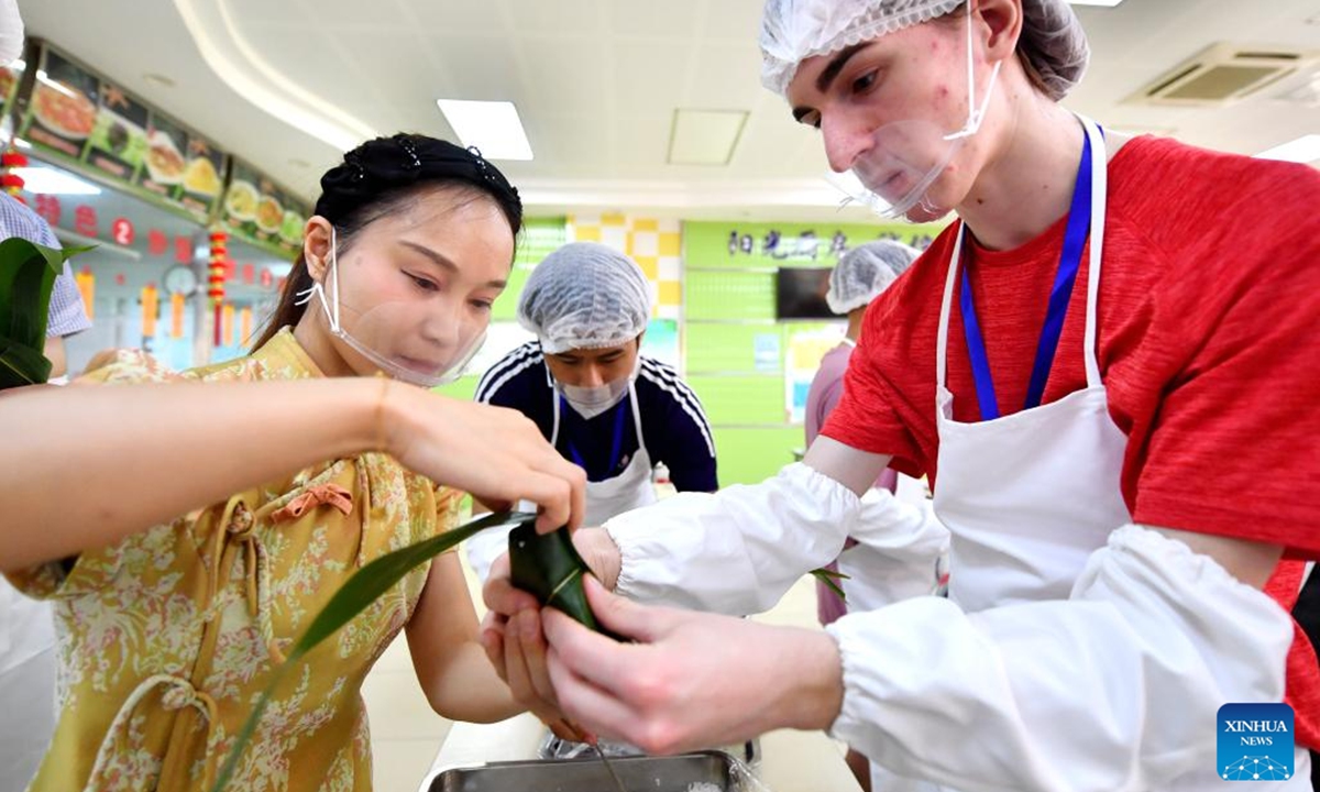 A member (R) of a delegation from U.S. state Iowa learns to make Zongzi, the glutinous rice dumplings wrapped in bamboo or reed leaves, during a cultural event at Shijiazhuang Foreign Language School in Shijiazhuang, north China's Hebei Province, June 8, 2024. A delegation of 51 students and teachers from U.S. state Iowa took part in a cultural event to greet the Duanwu Festival, or the Dragon Boat Festival, in Shijiangzhuang on Saturday. (Xinhua/Wang Xiao)


