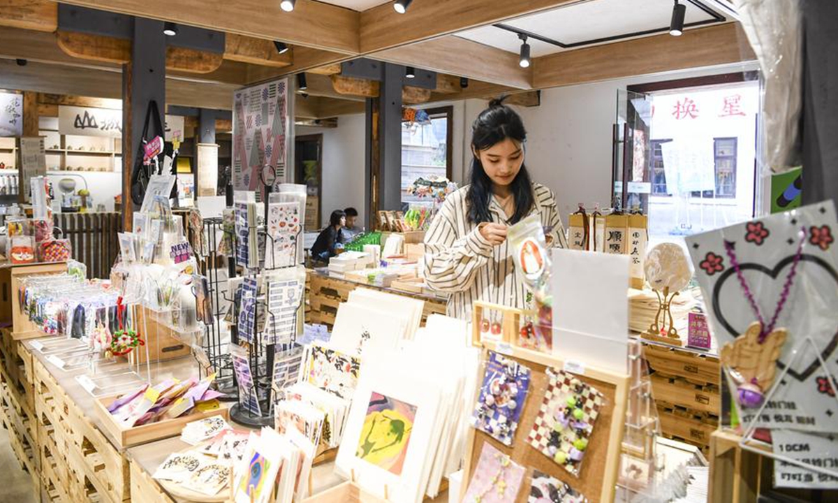 A tourist shops for cultural and creative products at a shop in Shancheng Alley in Yuzhong District, southwest China's Chongqing Municipality, June 5, 2024.(Xinhua/Wang Quanchao)
