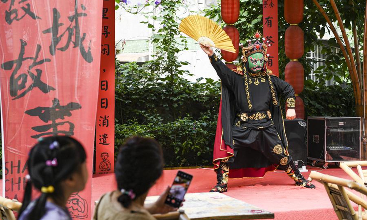 Tourists enjoy face-changing performance of Sichuan Opera at an open-air teahouse in Shancheng Alley in Yuzhong District, southwest China's Chongqing Municipality, May 30, 2024. (Xinhua/Wang Quanchao)
