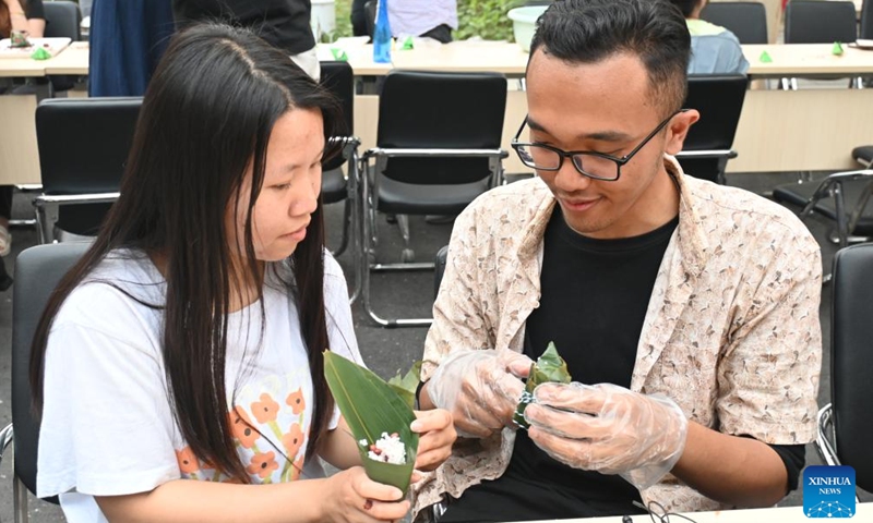 An international student from Indonesia (R) makes zongzi under the instruction of a tutor in north China's Tianjin Municipality, June 6, 2024. (Photo: Xinhua)