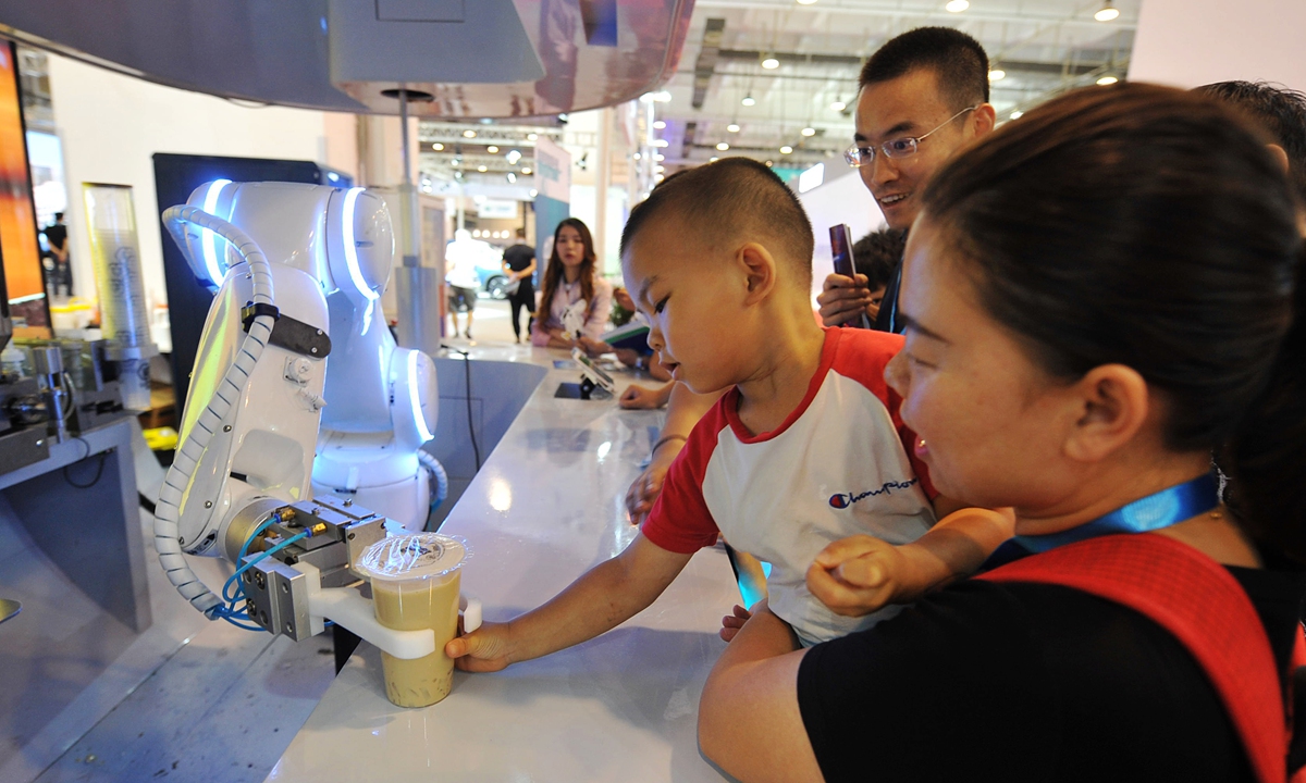 A kid takes a cup of milk tea made by a robot. Photo: VCG