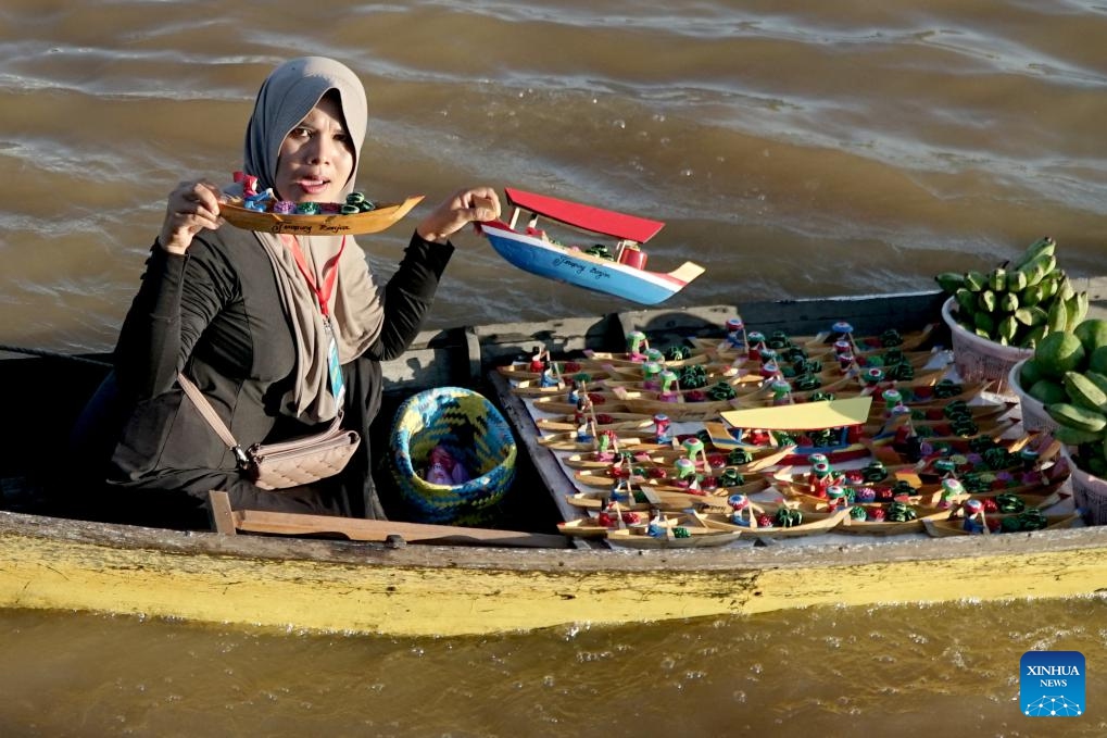 A vendor riding in a klotok boat offers model wooden boats to costumers at a floating market of Lok Baintan village in Banjar regency, South Kalimantan, Indonesia, June 12, 2024.(Photo: Xinhua)