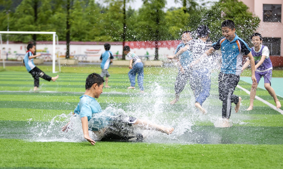 A group of elementary school students play in pooling water after heavy rain in Xinyu, East China's Jiangxi Province, on June 12, 2024. Photo: VCG