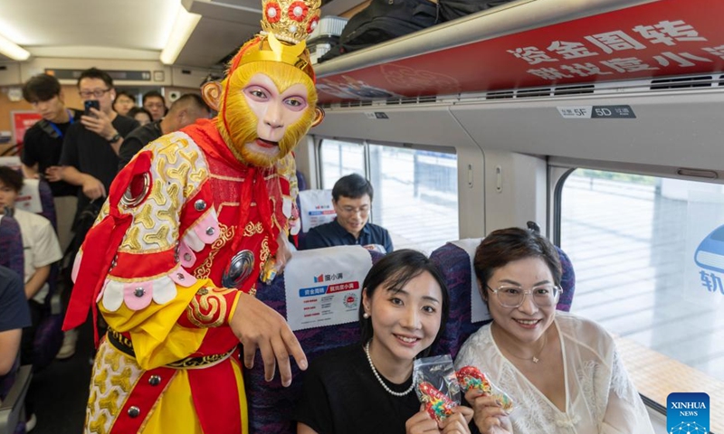 An performer in the costume of Monkey King presents souvenirs for passengers on the train G8388, June 15, 2024. 