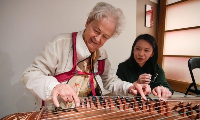 A woman (L) tries traditional Chinese musical instrument guzheng during the Getting to Know Chinese Folk Musical Instruments event at the Chinatown Storytelling Centre in Vancouver, British Columbia, Canada, on June 15, 2024.  (Photo: Xinhua)