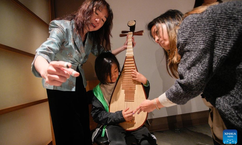 A Chinese music performer guides a child in playing traditional Chinese musical instrument pipa during the Getting to Know Chinese Folk Musical Instruments event at the Chinatown Storytelling Centre in Vancouver, British Columbia, Canada, on June 15, 2024. The event held here on Saturday allowed participants to hold and play traditional Chinese instruments, immersing themselves in the rich cultural heritage of Chinese music. (Photo: Xinhua)