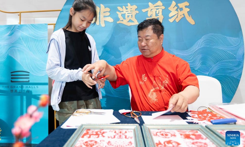 A child learns paper cutting skills at the Grand Halls in Shanghai, east China, June 16, 2024. The first public open day of the Grand Halls was launched in Shanghai on Sunday, attracting many visitors. Consisting of three old buildings with an area of 99,000 square meters, the Grand Halls previously was the Yangtze River wharf with a history of more than 100 years. (Photo: Xinhua)