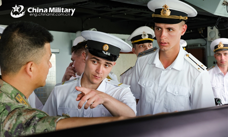 A Chinese naval officer answers questions asked by visiting Russian sailors about the Chinese vessel during the China-Russia joint naval exercise coded Exercise Joint Sea-2024 on July 13, 2024. (eng.chinamil.com.cn/Photo by Luan Cheng)