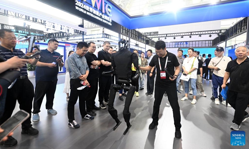 A staff member interacts with a humanoid robot at the World Intelligence Expo 2024 in north China's Tianjin, June 21, 2024. From coffee robots to humanoid robots, the four-day expo highlighted the diverse application scenarios of robots.