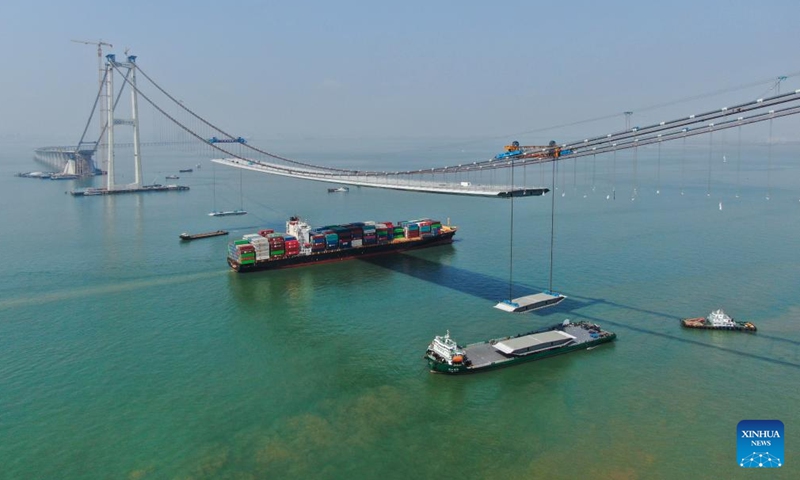 An aerial drone photo taken on Feb. 22, 2023 shows a container ship passing under Shenzhong Bridge of the Shenzhen-Zhongshan link under construction in south China's Guangdong Province.