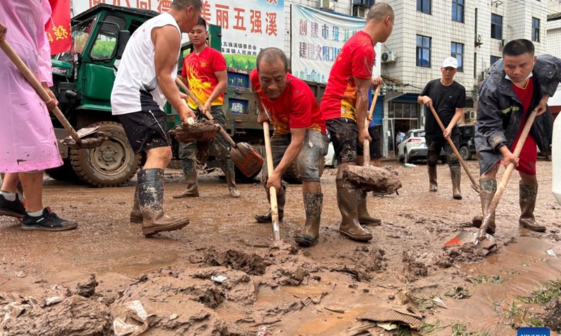 This photo taken by a mobile phone on June 23, 2024 shows people cleaning the mud on a road in Wuqiangxi Township of Yuanling County in central China's Hunan Province. Heavy rainfall hit Wuqiangxi Township on Saturday, triggering flood that impacted local residential area. Local authorities have carried out emergency response to minimize the impact of the extreme weather conditions. (Photo: Xinhua)