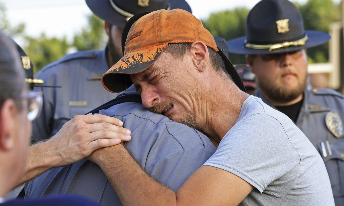 Bo Lanthrop (right) cries in the arms of a member of the Fordyce Police Department during a candlelight vigil on June 23, 2024, at the Mad Butcher grocery store in a small town in Arkansas, US, where a mass shooting took place on June 21, killing four and injuring nine others. Photo: VCG