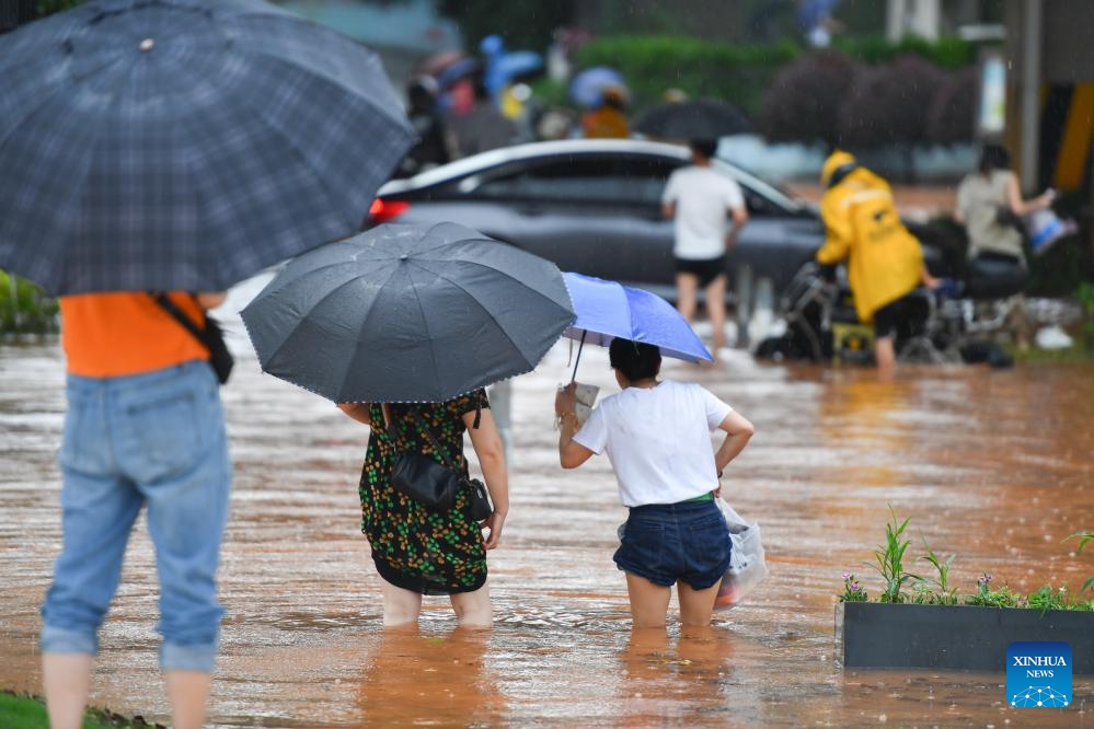 People wade through a waterlogged road in Changsha, central China's Hunan Province, June 24, 2024. On Monday, Changsha of central China's Hunan Province saw 15 waterlogged roads after intense rain. The city has launched a Level III emergency response for floods(Photo: Xinhua)