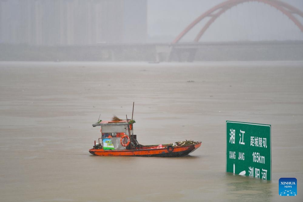 A garbage removal boat passes by a navigation sign submerged in the Xiangjiang River in Changsha, central China's Hunan Province, June 26, 2024. Due to continuous heavy rainfall, water level recorded at the Changsha hydrological observation station reached to 36.75 meters at 1:32 p.m. on Wednesday, 0.75 meters above the alert line.(Photo: Xinhua)