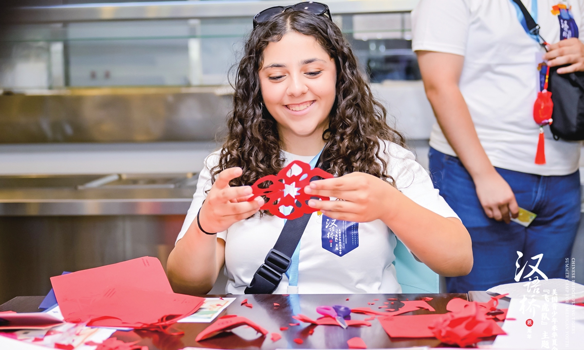 An American student experiences paper cutting at the camp opening ceremony in Beijing on June 26.  