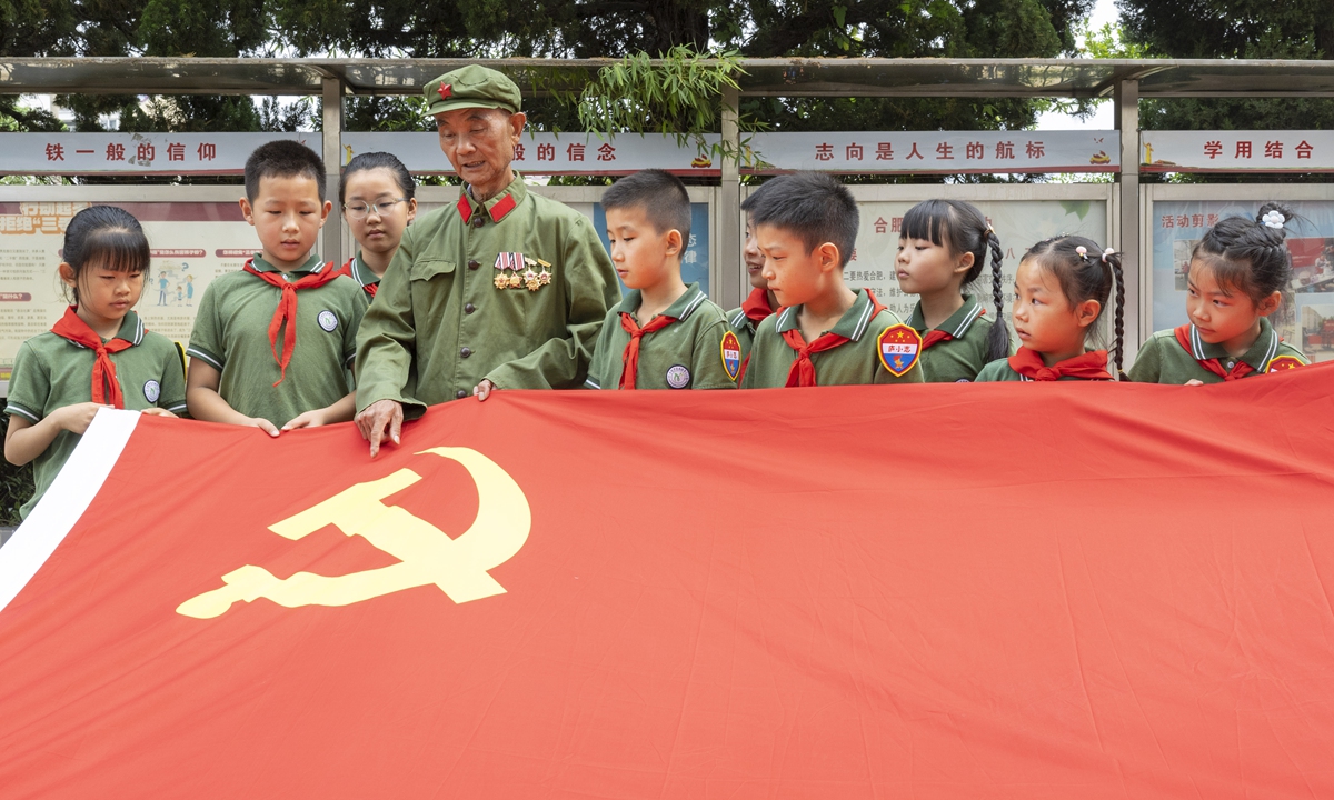 An elderly Party member gives a lecture on the history of the Party flag to elementary school students in Hefei, East China's Anhui Province, on June 25, 2024. Photo: VCG