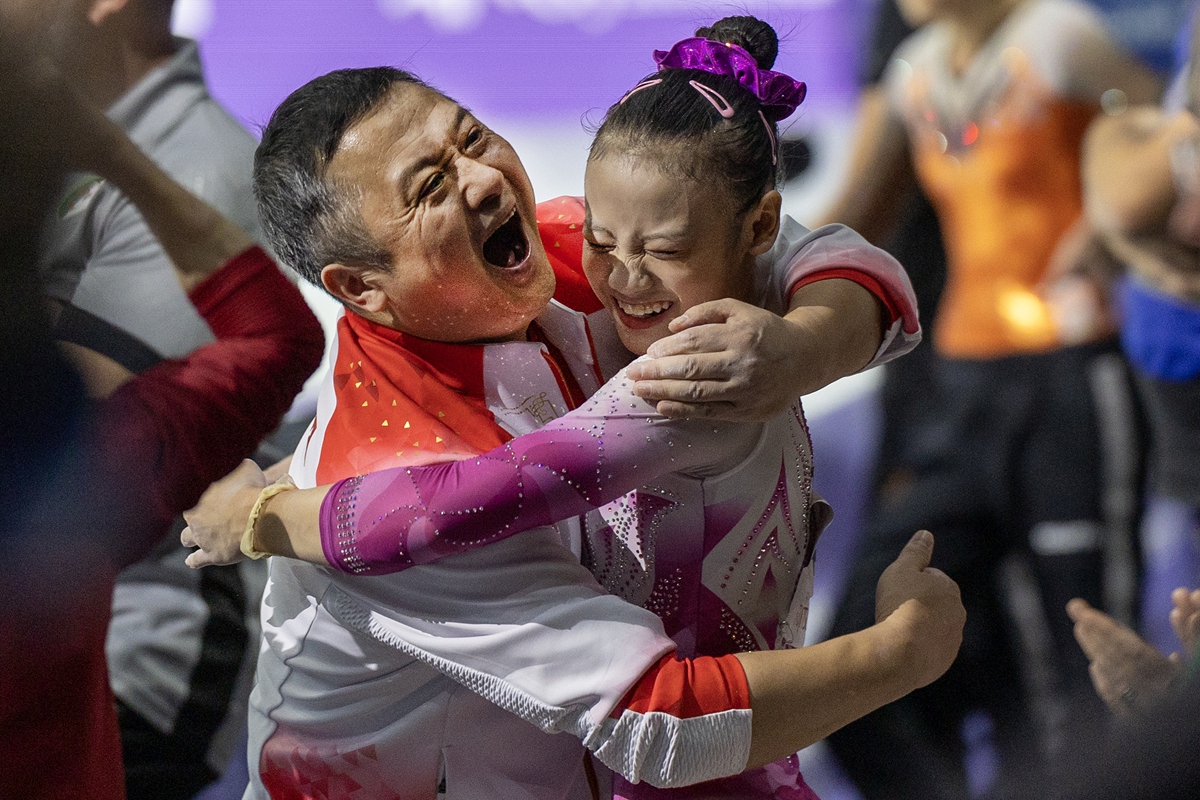 Qiu Qiyuan celebrates with her coach after winning gold in the women's uneven bars final on October 7, 2023 in Antwerp, Belgium. Photo: VCG