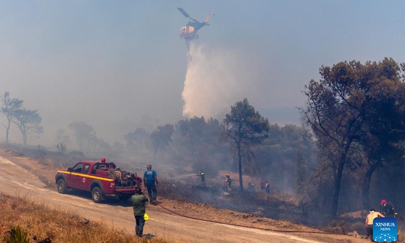 A firefighting helicopter drops water on a wildfire in the forest at Keratea, southeast of Athens, Greece, June 30, 2024.Since the start of the wildfire season on May 1, firefighters are called to handle dozens of wildfires every day across the country. (Xinhua/Marios Lolos)