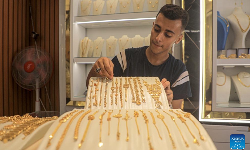 A merchant displays gold jewelry at a gold shop in the southern Gaza Strip city of Khan Younis, on June 26, 2024. (Photo by Rizek Abdeljawad/Xinhua)