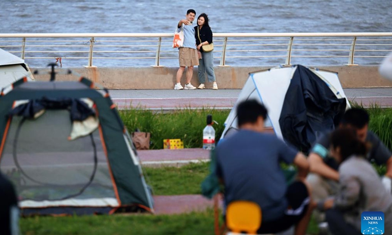 People pose for selfies at a park in the Binhai New Area of north China's Tianjin, June 29, 2024. Over the years, the city of Tianjin has worked on the ecological restoration and development of Bohai Sea.