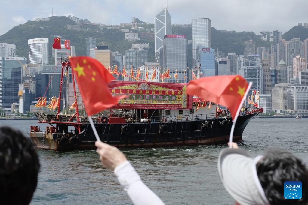 Citizens wave Chinese national flags at a fishing vessel during a cruise held by the Hong Kong Fishermen Consortium to celebrate the 27th anniversary of Hong Kong's return to the motherland at Victoria Harbour in Hong Kong, south China, July 1, 2024. (Photo: Xinhua)