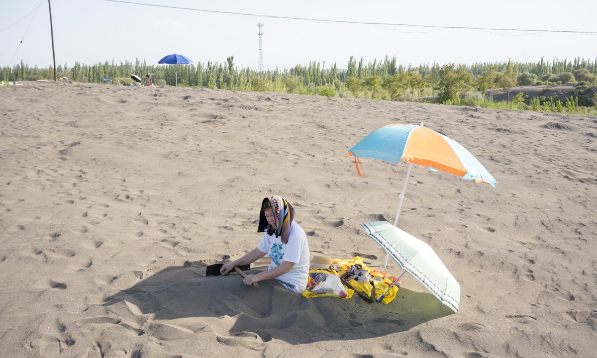 A woman enjoys sand therapy in Turpan City, Northwest China's Xinjiang Uygur Autonomous Region. Photo: VCG