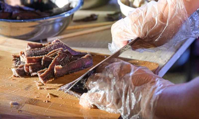 An assistant of a competitor slices dried meat during a sour rice noodle cooking competition in Lingshui, south China's Hainan Province, July 26, 2024. Lingshui sour rice noodle is a popular local snack and was listed as a provincial-level intangible cultural heritage in 2009. Recently a cooking competition was held in Lingshui to promote the sour rice noodle industry. Photo: Xinhua