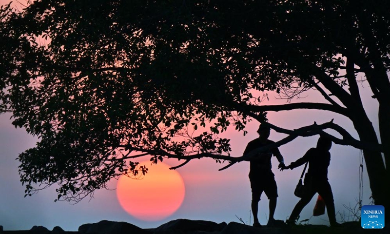 People view the sunset at a seaside in Jerudong, Brunei, July 26, 2024. (Photo by Jeffery Wong/Xinhua)