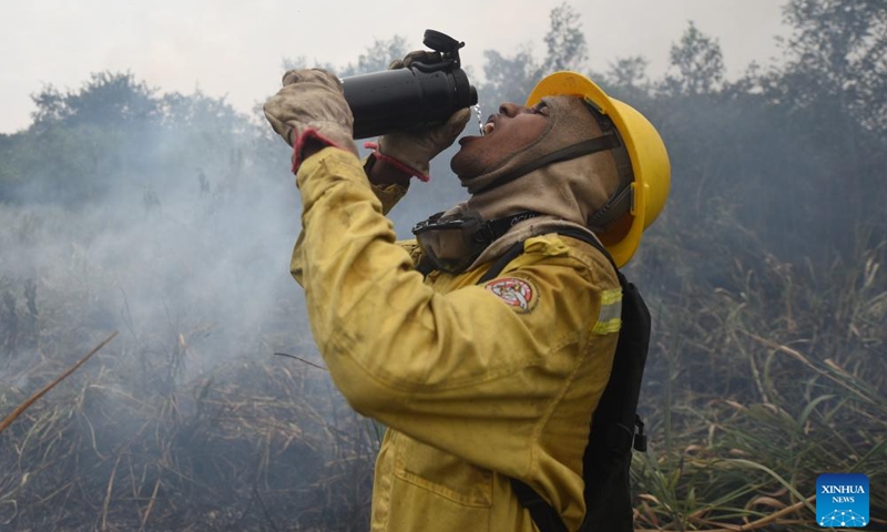 A firefighter drinks water during a break in firefighting operations along Paraguay River in Pantanal, in Corumba, Mato Grosso do Sul, Brazil, July 7, 2024. (Photo by Lucio Tavora/Xinhua)