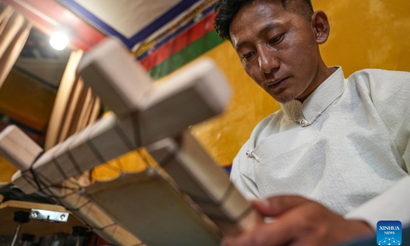 Tenzin Tegchok, a former thangka painter, creates a painting at his cafe on the Barkhor Street in Lhasa, southwest China's Xizang Autonomous Region, July 5, 2024. 