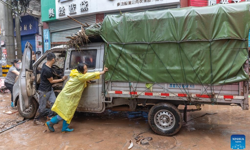 Local people clean up a flooded vehicle in Sanhui Town of Zhongxian County, southwest China's Chongqing, July 11, 2024. Torrential rains have recently hit Zhongxian County in Chongqing. After the flood receded, efforts were made to clean up the road, fix infrastructures and investigate hidden dangers in the hard-hit Sanhui Town. (Photo: Xinhua)