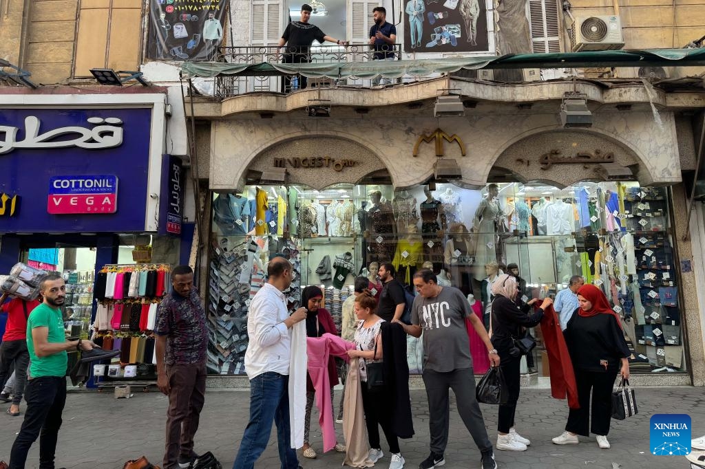 People stand in front of clothing stores in Cairo, Egypt, on July 10, 2024. Egypt's annual headline inflation rate dropped to 27.1 percent in June, down from 27.4 percent in May, continuing a downward trend for the fourth consecutive month, the country's statistics body reported on Wednesday (Photo: Xinhua)