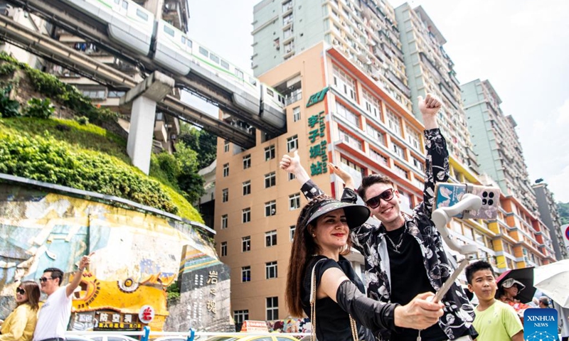 Ilia Anfilatov and Syyra Alee take videos at a popular tourist destination in southwest China's Chongqing Municipality, July 12, 2024. (Xinhua/Tang Yi)