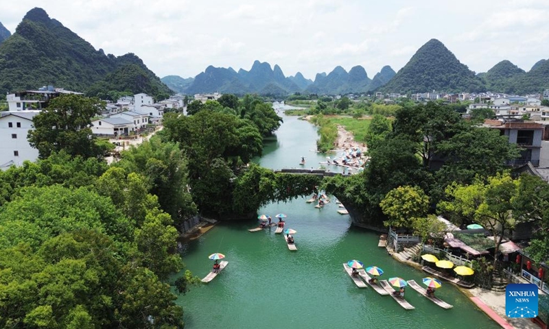 An aerial drone photo taken on July 14, 2024 shows tourists riding on bamboo rafts in a river of Yangshuo County, Guilin City, south China's Guangxi Zhuang Autonomous Region. Many tourist destinations across China have recently seen a surge in visitors as the country enters its peak summer tourist season. (Photo by Liao Zuping/Xinhua)