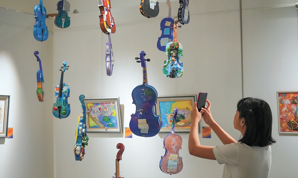 A woman takes photos of exhibits at the 9th International Children's Creative Art Exhibition in Shanghai on July 16, 2024, the exhibition's opening day. This year's exhibition attracted young artists from more than 20 countries, while around 160 exhibits were selected from among hundreds of submitted artworks. Photo: Lu Ting/GT