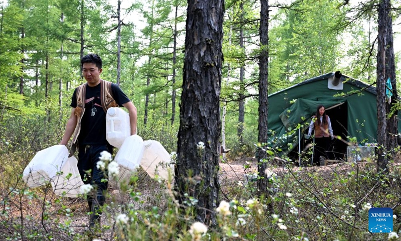 Wu Qiming prepares to fetch water from a stream near the reindeer herding site in Jinhe Town of Genhe City, north China's Inner Mongolia Autonomous Region, July 3, 2024. (Xinhua/Bei He)