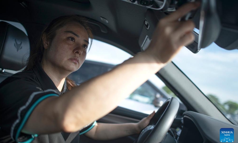 Intelligent connected vehicle tester Wang Juan adjusts a rearview mirror before a road test in Wuhan, central China's Hubei Province, July 4, 2024. 