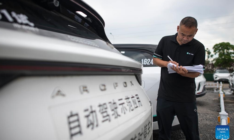 Intelligent connected vehicle tester Li Cheng checks a vehicle after a road test in Wuhan, central China's Hubei Province, July 4, 2024.