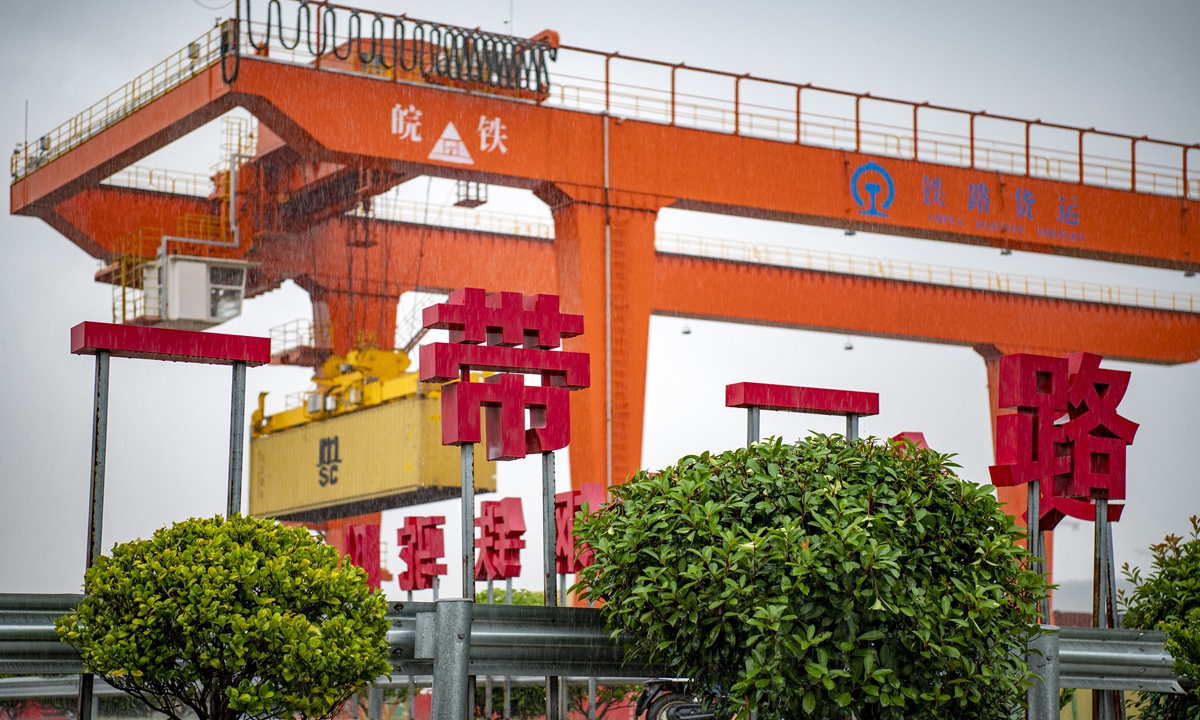 A large crane loads containers for a China-Europe freight 
train is behind a banner displaying the 