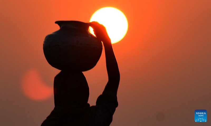 This photo taken on July 17, 2024 shows the silhouette of a woman walking at sunset carrying a water pot on her head in southern Pakistan's Hyderabad. (Photo: Xinhua)