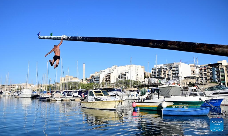 A contestant participates in the greasy pole competition in Msida, Malta, on July 21, 2024. (Photo by Jonathan Borg/Xinhua)