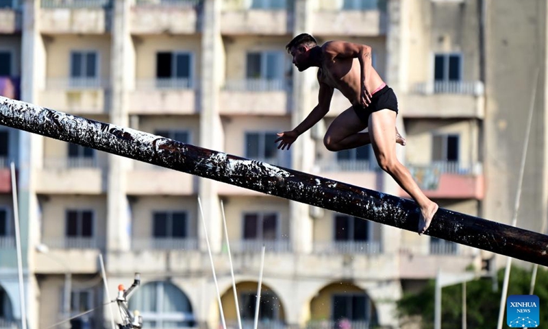 A contestant participates in the greasy pole competition in Msida, Malta, on July 21, 2024. (Photo by Jonathan Borg/Xinhua)