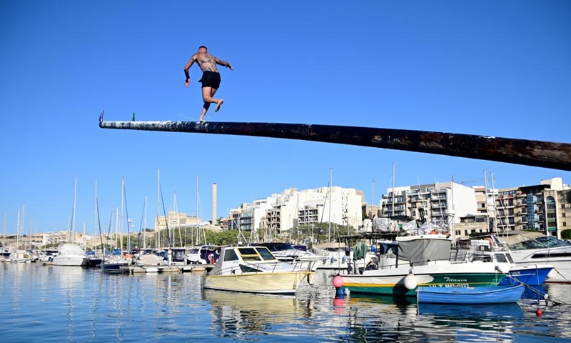 A contestant participates in the greasy pole competition in Msida, Malta, on July 21, 2024. (Photo by Jonathan Borg/Xinhua)